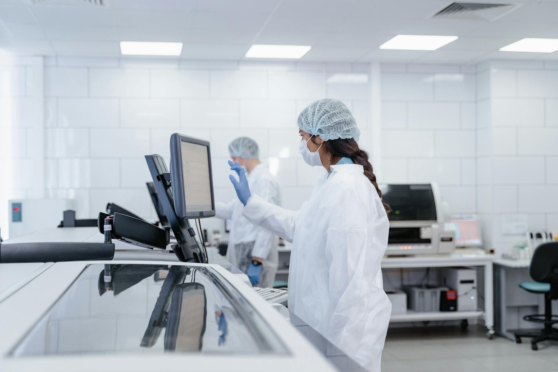 Scientist in protective gear operates equipment in a modern lab.