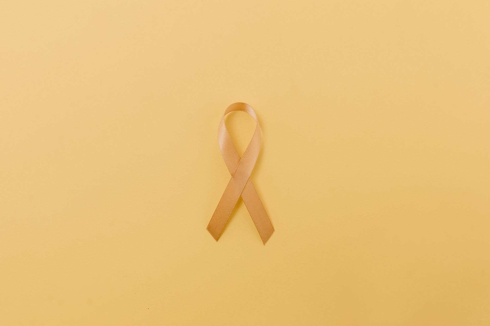 Gold ribbon symbol on a yellow background representing childhood cancer awareness.