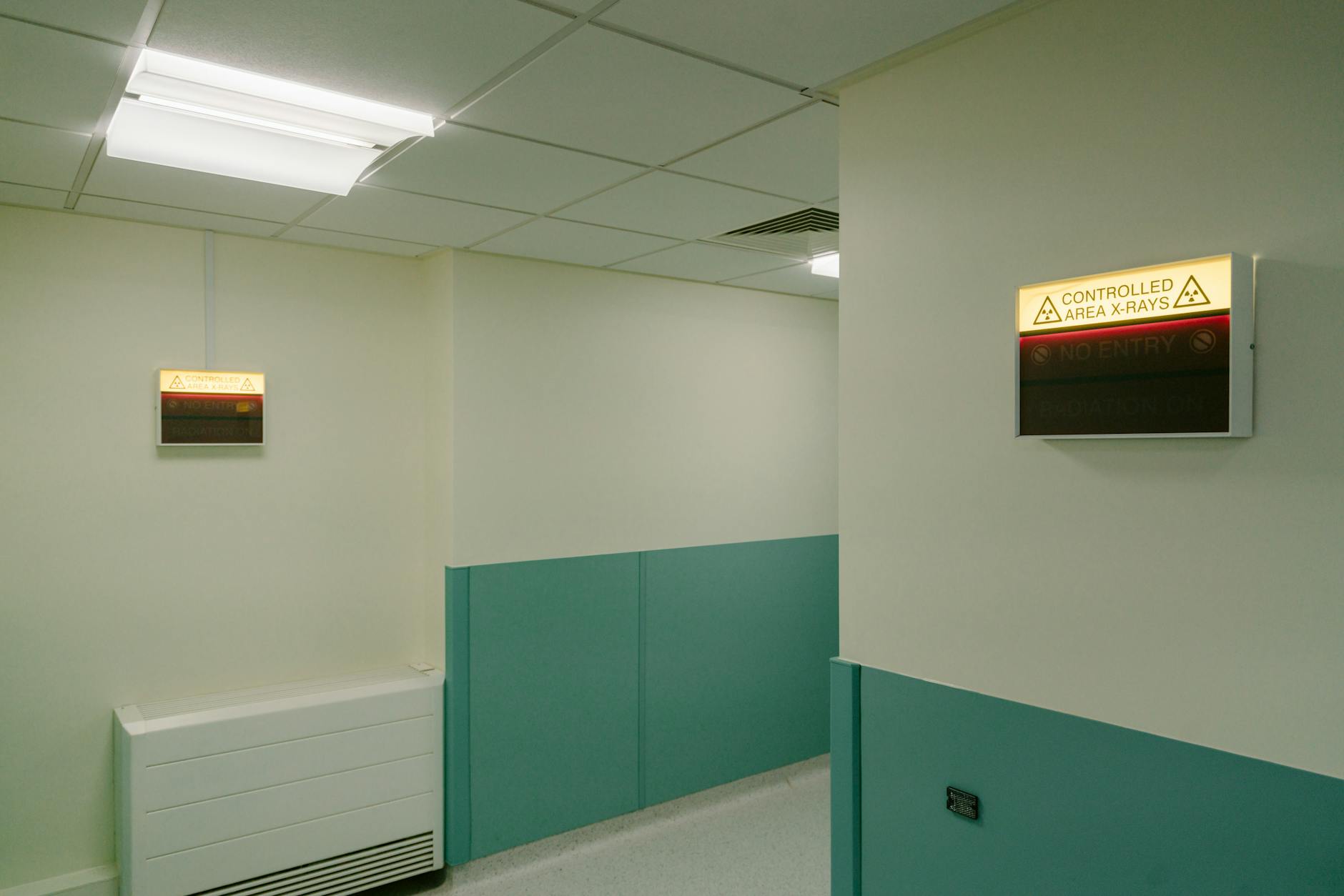 Interior hospital hallway with illuminated X-Ray area warning signs.